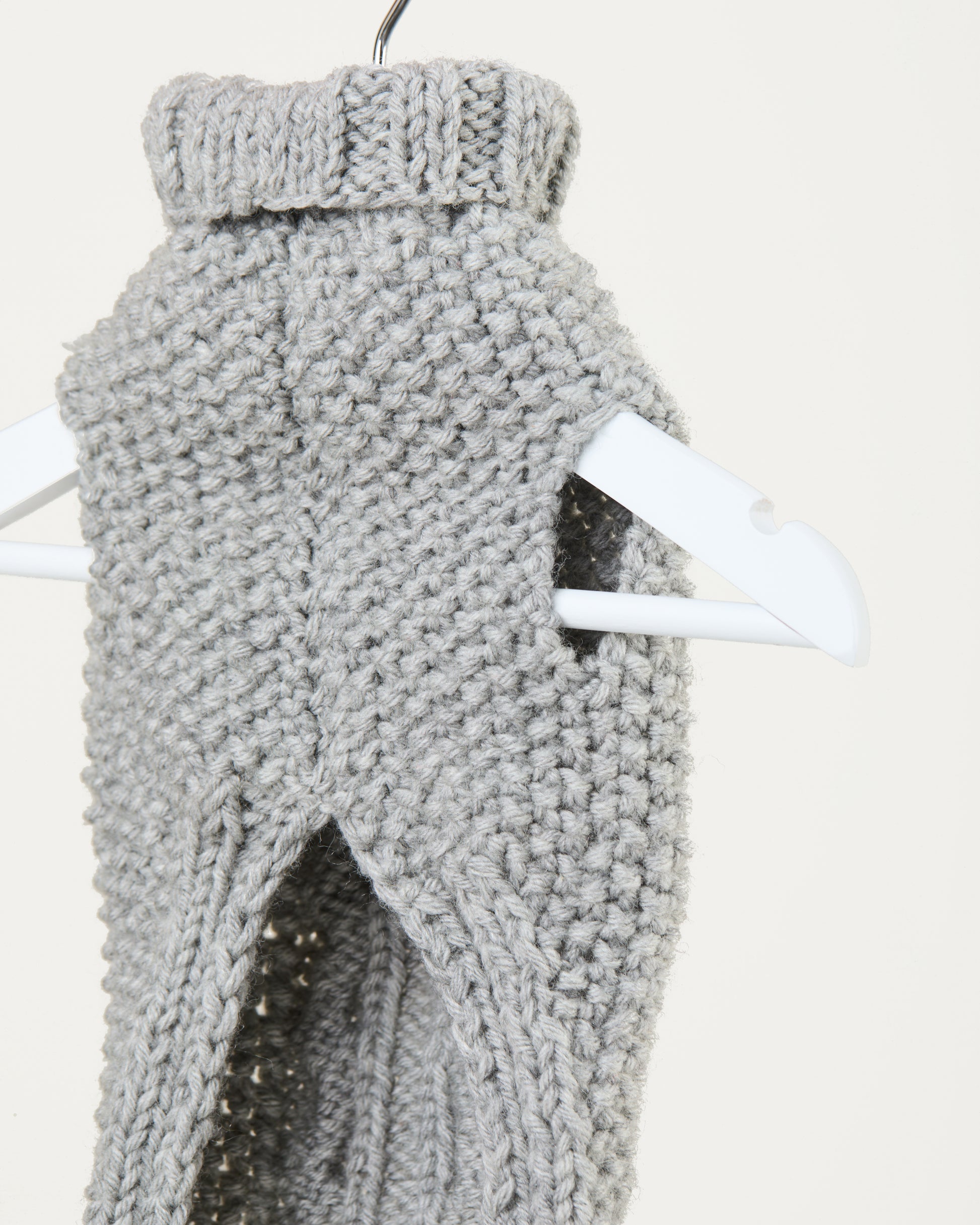 Gray knitted vest on a hanger against a white background