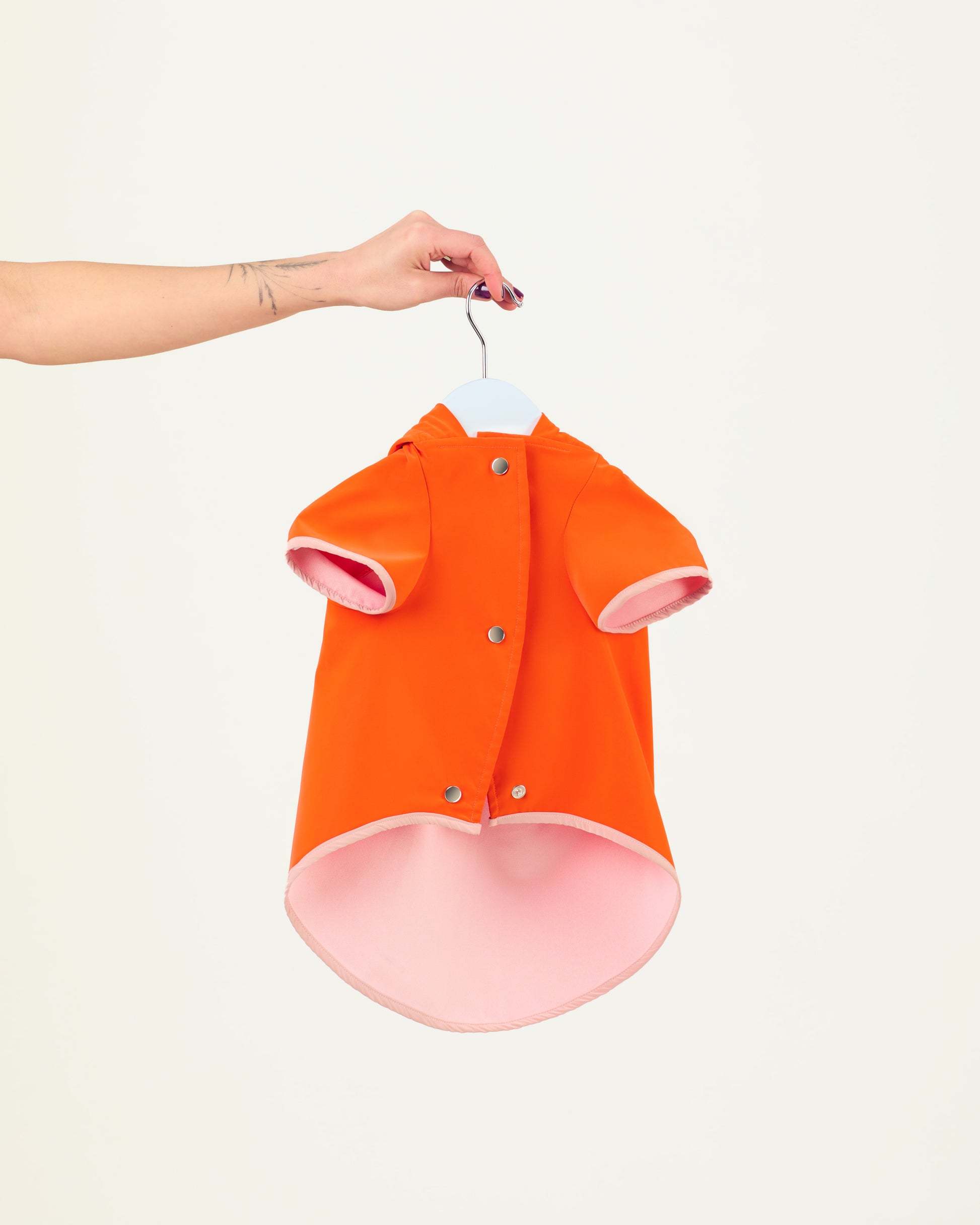 Orange dog raincoat on a hanger against a white background
