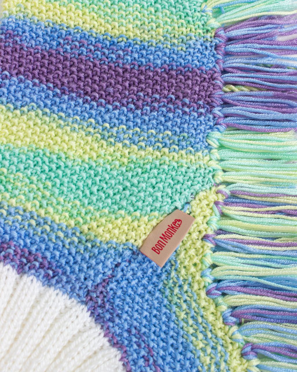 Colorful knitted dog poncho with a brand tag on a white background