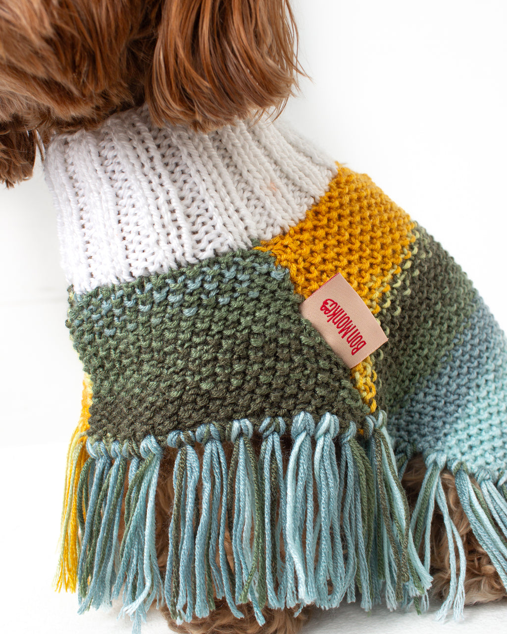 handmade dog poncho with colorful yarn and brand tag on a white background