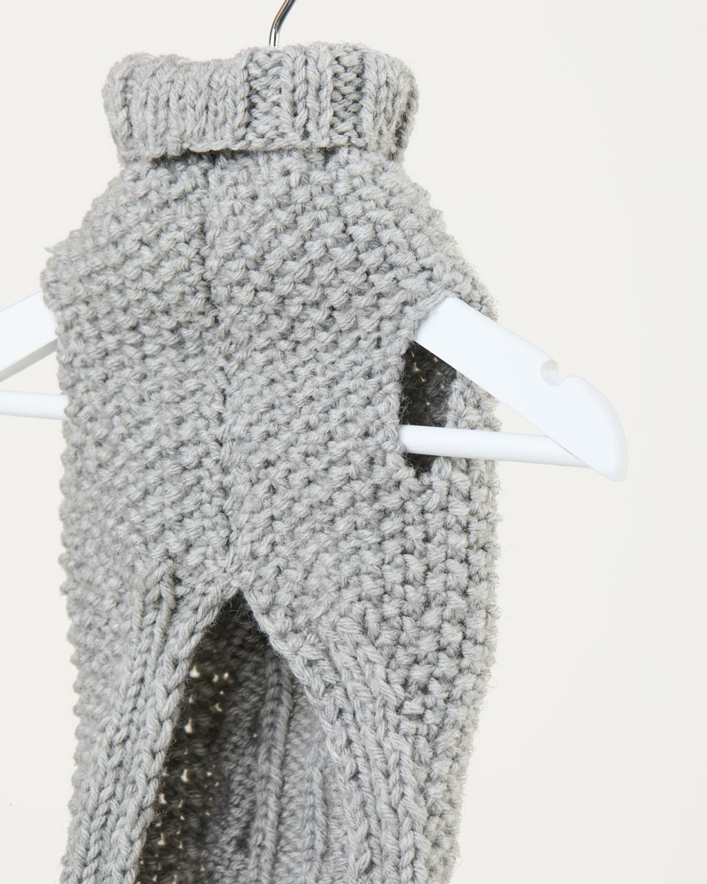 Gray knitted vest on a hanger against a white background